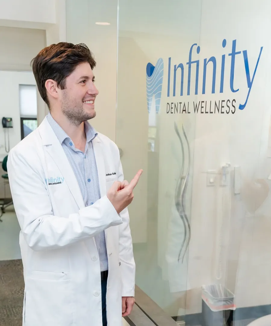 Dr. Jonathan Odinsky beside the Infinity Dental Wellness logo in the Fort Lee, NJ office